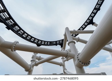 Attraction roller-coaster with the background of the cloudy sky.