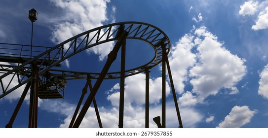 Attraction roller-coaster (switchback) on the background of the cloudy sky 