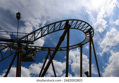 Attraction roller-coaster (switchback) on the background of the cloudy sky 