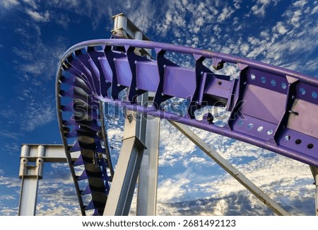 Attraction roller-coaster (switchback) on the background of the cloudy sky 
