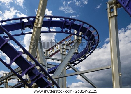 Attraction roller-coaster (switchback) on the background of the cloudy sky 