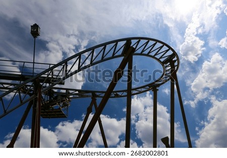 Attraction roller-coaster (switchback) on the background of the cloudy sky 