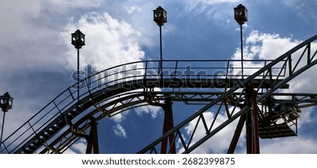 Attraction roller-coaster (switchback) on the background of the cloudy sky 