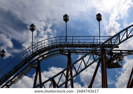 Attraction roller-coaster (switchback) on the background of the cloudy sky 