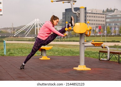 Attractive adn beautiful fit girl is stretching alone on the training bars