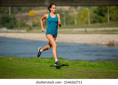 Attractive adn beautiful fit girl is running slowly on the grass