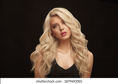 Attractive adult girl with long blonde hair and natural clean skin posing on a black isolated background.