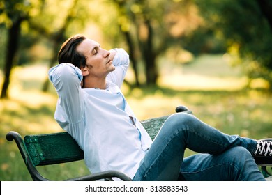 Attractive Adult Man Sitting Alone On Bench In Park