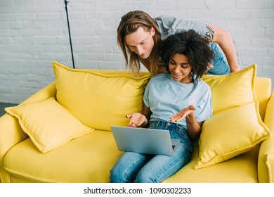 attractive african american woman pointing on laptop screen to boyfriend 