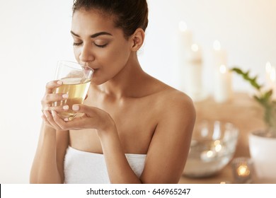 Attractive African Girl Drinking Green Tea Resting In Spa Salon. Closed Eyes.