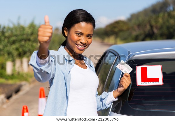 attractive african learner driver holding her\
driver\'s license
