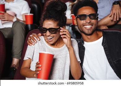 Attractive afro american couple watching 3D movie and laughing while sitting in a movie theater