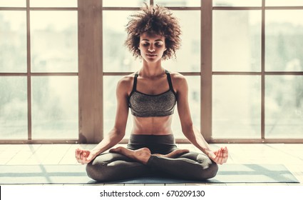 Attractive Afro American girl in sportswear is meditating while doing yoga - Powered by Shutterstock