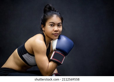 Attractive Asian Boxer Woman Sitting And Posing With Blue Boxing Gloves In Fitness Gym. Female Boxing Class And Martial Art Concept