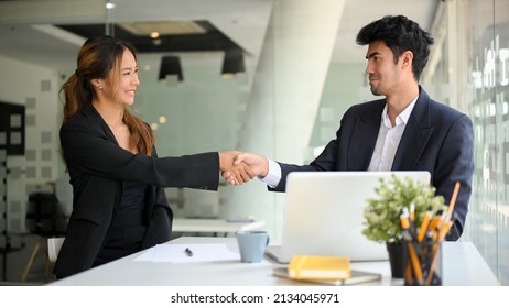 Attractive Asian Businesswoman Shakes Hands With A Successful Male Entrepreneur In The Business Meeting. Male Boss Shakes Hands And Welcomes The New Female Employee.