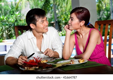 An Attractive Asian Couple Eating Together At A Restaurant