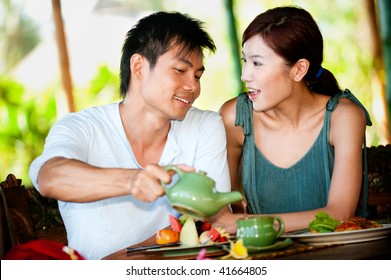 An Attractive Asian Couple Eating Together At A Restaurant