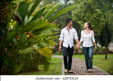 Attractive Asian Couple Walking Hand In Hand In Park