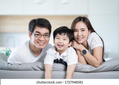 Attractive Asian Family Smile Happiness Looking Camera Portrait Sitting On Sofa At Home, Dad Mom And Son Happy Concept.