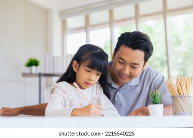 Attractive Asian Father Teaching Little Child Daughter Learning Studying Doing Homework At Home, Family Quality Time And E-learning Education Concept