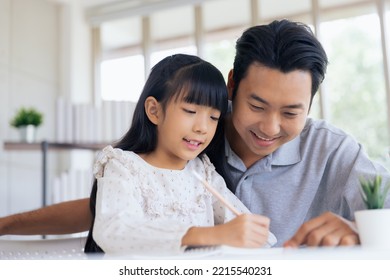 Attractive Asian Father Teaching Little Child Daughter Learning Studying Doing Homework At Home, Family Quality Time And E-learning Education Concept