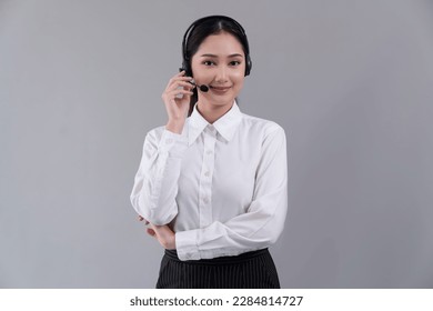 Attractive asian female call center operator with happy smile face advertises job opportunity on empty space, wearing a formal suit and headset on customizable isolated background. Enthusiastic - Powered by Shutterstock