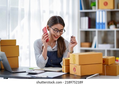 Attractive Asian Female Entrepreneur Woman Work With A Smartphone, Young Asian Small Business Owner Use Computer, Online Market Packing Box Delivery, SME E-commerce Telemarketing Concept