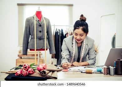 Attractive Asian Female Fashion Designer  Working In Home Office Workshop. Stylish Fashionista Woman Creating New Cloth Design Collection. Tailor And Sewing. People Lifestyle And Occupation Concept