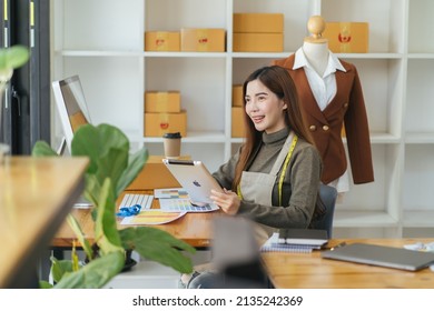 Attractive Asian Female Fashion Designer Working In Home Office Workshop. Stylish Fashionista Women Creating New Cloth Design Collection. Tailor And Sewing. People Lifestyle And Occupation Concept.