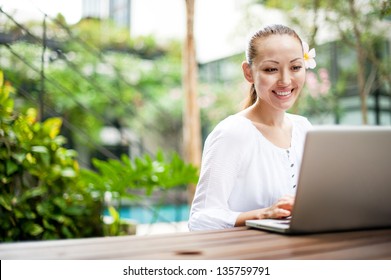 Attractive Asian Female using a laptop in the park enjoying the internet