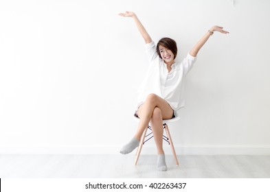 Attractive Asian girl sitting on white modern chair and relax at home.