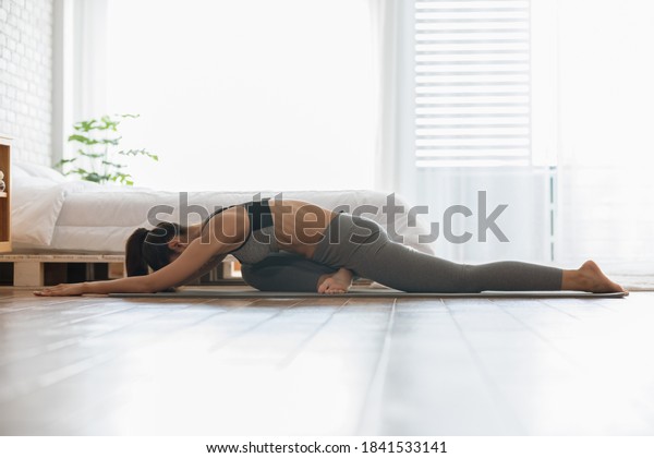 Attractive Asian indian woman practice yoga\
pigeon pose to meditation at home Feeling so calm comfortable and\
relax,Yoga for Healthcare\
Concept