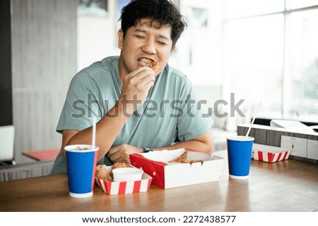 Attractive Asian man eating fried chicken