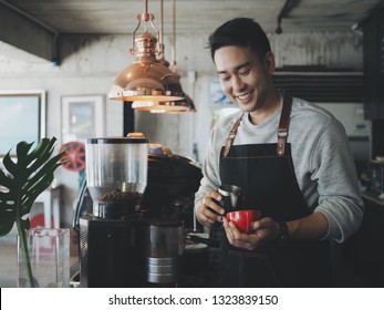 Attractive Asian Man Making Coffee In His Cafe.