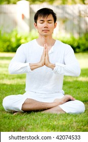 An Attractive Asian Man Meditating Outdoors In A Garden