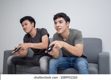 Attractive Asian Man Playing Videogames On Tv With Friend. People Play Game With Happy Emotion Togeyher. People Lifestyle Concept.