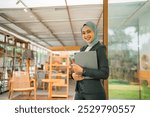 attractive Asian Muslim woman business owner holding a tablet while working