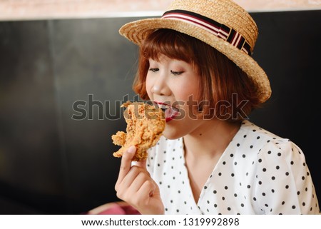 Attractive Asian woman eating fried chicken.