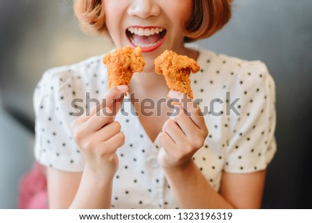 Attractive Asian woman eating fried chicken.