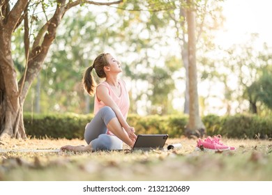 Attractive Asian woman healthy in sportswear workout practice yoga online with tablet in nature park outdoor under sunset. Healthy lifestyle and relaxation. - Powered by Shutterstock