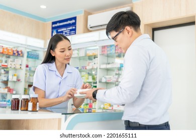 Attractive Asian Woman Pharmacist Medication Recommendation About Medicine, Drugs And Supplements To Male Patient Customer In Modern Drugstore. Medical Pharmacy And Healthcare Providers Concept.