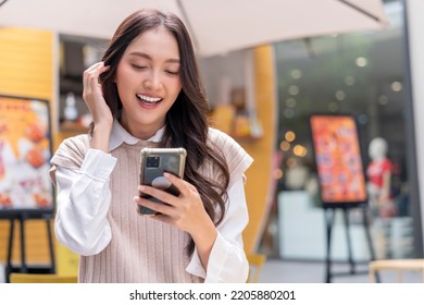 Attractive Asian Woman Pleased Positive Casual Hand Hold Smartphone Enjoy Leisure Relas Sitting In Front Of Street Food Booth Corner In Outlet Department Store Mall Relax Shopping Lifestyle Concept