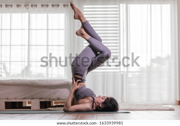 Attractive Asian\
woman practice yoga Shoulder stand with Eagle leg pose to\
meditation in bedroom after wake up in the morning Feeling so\
comfortable and relax,Healthcare\
Concept