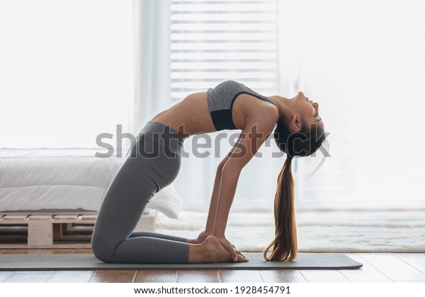 Attractive Asian woman practice yoga Ustrasana\
pose or yoga Camel pose deep breath to meditation in bedroom after\
wake up in the morning Feeling so comfortable and relax,Yoga for\
Healthcare Concept