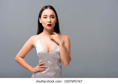 Attractive Asian Woman In Satin Dress With Red Lips Posing Isolated On Grey