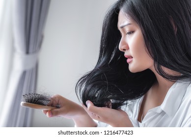 Attractive Asian woman serious about her brush for presentation hair loss problem and looking at comb