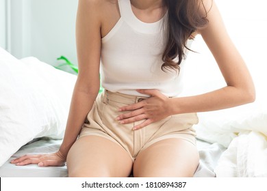 Attractive Asian Woman Sitting On Bed Have A Bladder Pain.