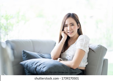 Attractive Asian Woman Sitting Portrait On Couch With Big Widow On Background