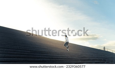 Attractive Asian woman in sportswear workout exercise jogging up on staircase at city street in the morning. Healthy girl enjoy outdoor active lifestyle do sport training fitness running in the city.