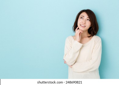 attractive asian woman thinking isolated on blue background